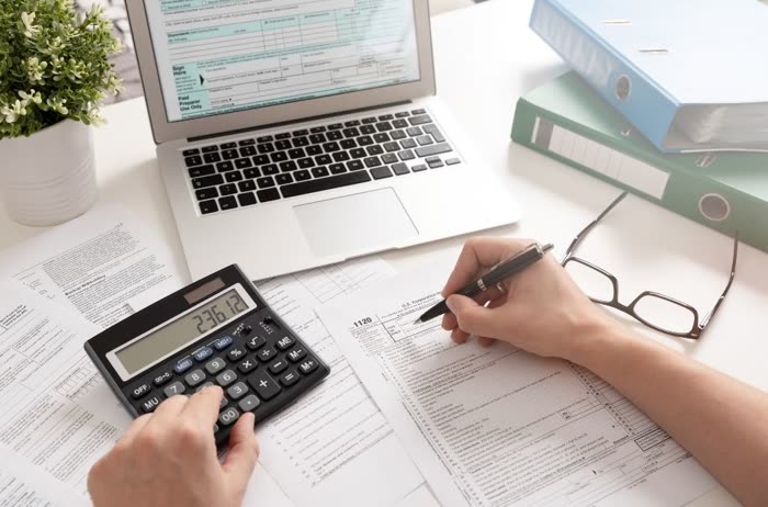 Profissional conferindo documentos fiscais com calculadora